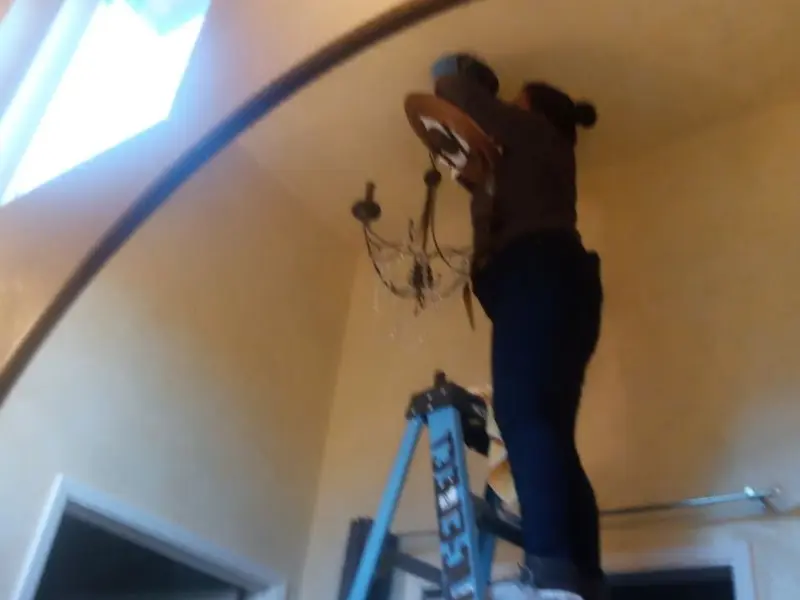 Electrician installing a chandelier in a Meredith residence